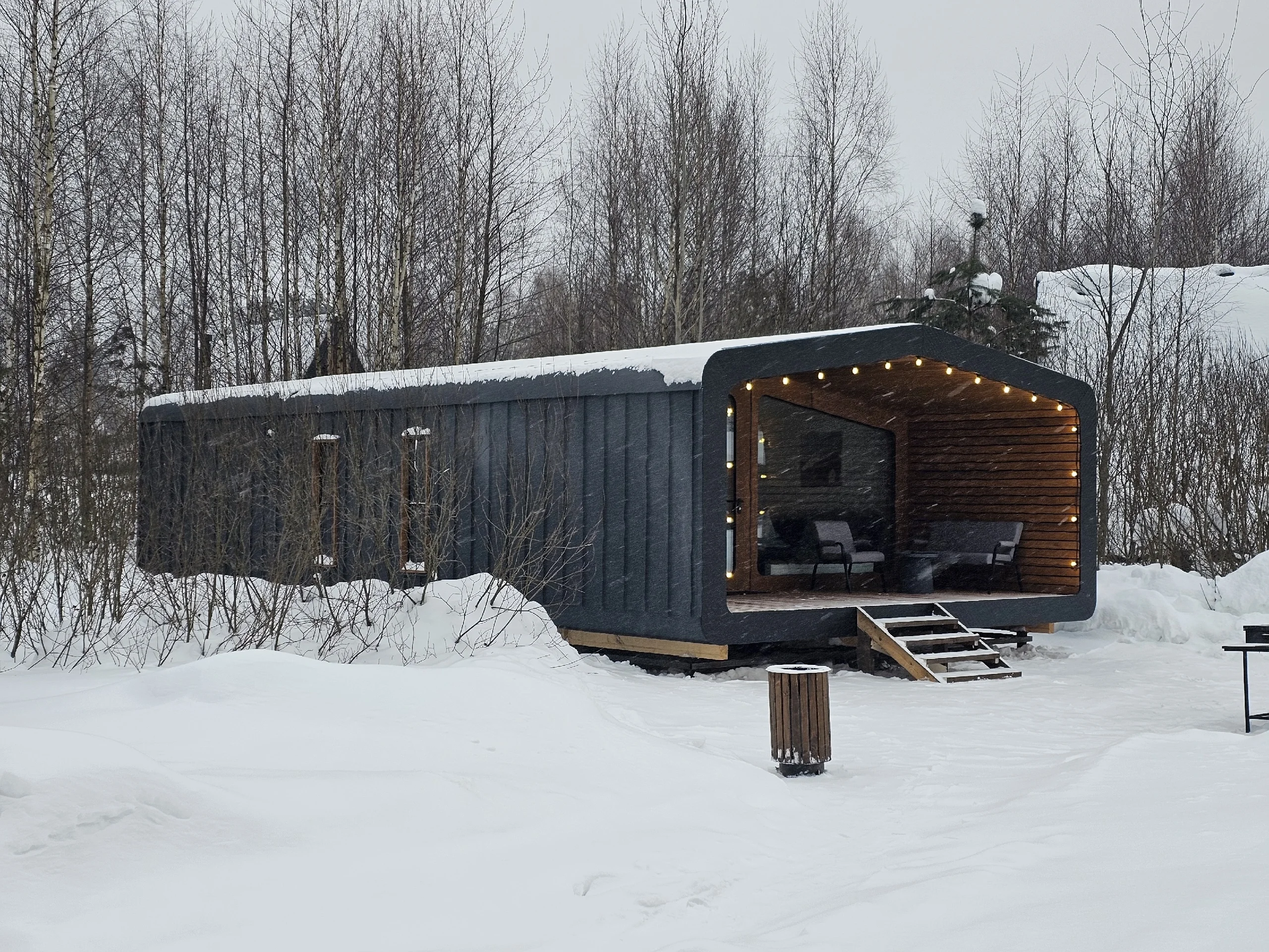 Built BARN 57 cabin with a covered veranda in a snowy woodland